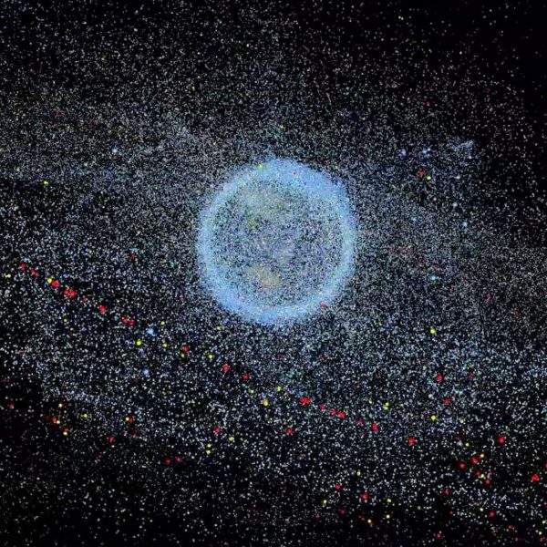 An image of the Earth appears on a black background. The Earth is swarmed by satellites and space debris that form a glowing, granular cloud around it.